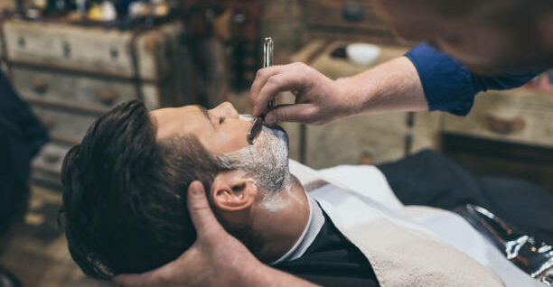 Barber shaving customers beard in vintage barber shop
